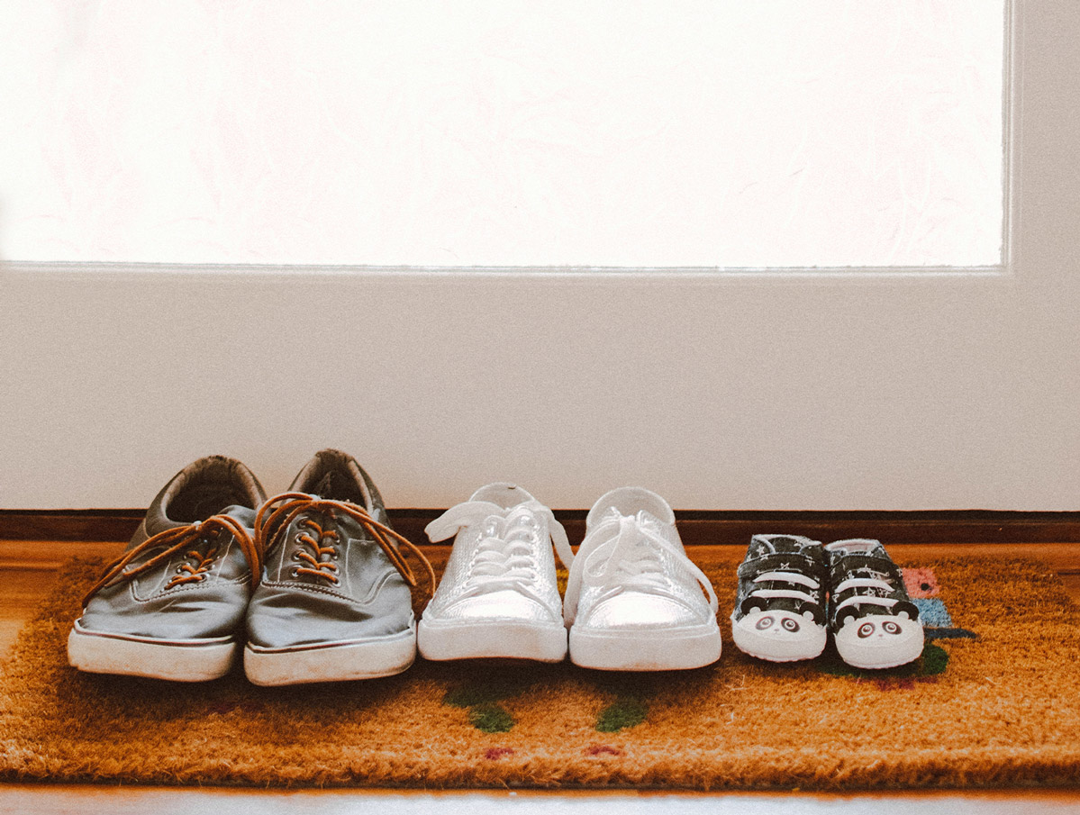 Three pairs of shoes resting on an entry mat.